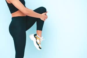 ספורטאית מבצעת מתיחות לרגליים. לשמירה על בריאות כף הרגל בעזרת פדיקור רפואי לספורטאים עד הבית שמסייעת במניעת פציעות עומס.