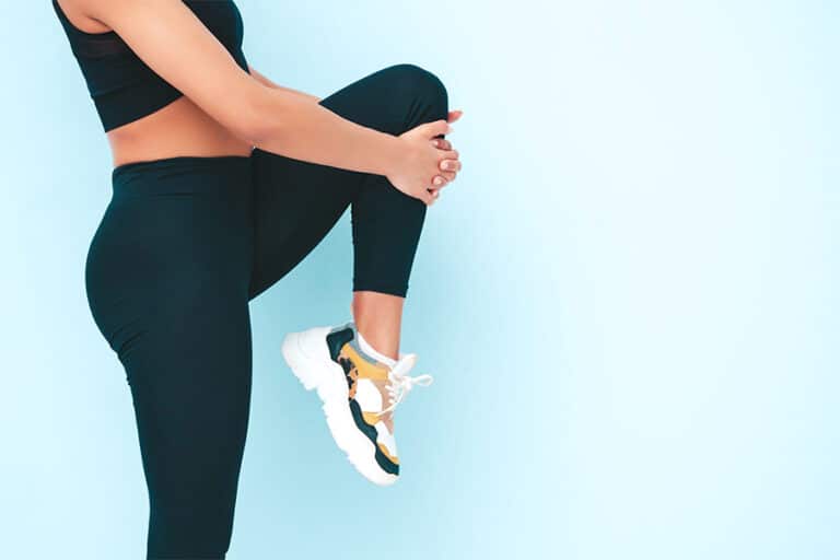 ספורטאית מבצעת מתיחות לרגליים. לשמירה על בריאות כף הרגל בעזרת פדיקור רפואי לספורטאים עד הבית שמסייעת במניעת פציעות עומס.